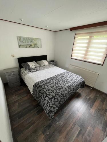 um quarto com uma cama e piso em madeira em Chalet 58 ''Pollie'' em Hattemerbroek