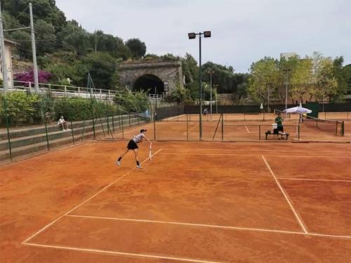 a man playing tennis on a tennis court at Gli Scogli Luxury Residence Hotel in Chiavari