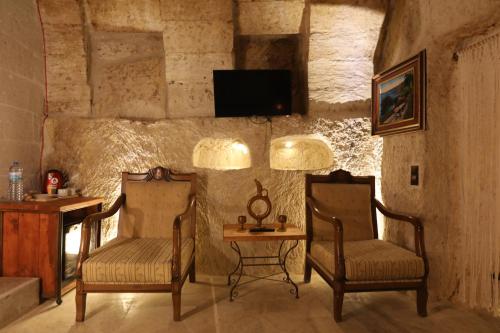 a room with two chairs and a table and a tv at Atax Cave House in Avanos