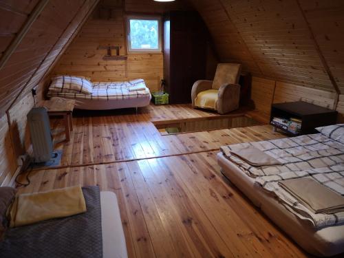 an attic room with two beds and a couch at domki nad jeziorem, las, do 10 osób jezioro Wilczyńskie Budzisławskie - domek letniskowy osobno ogrodzony, ogrzewany mile widziane pieski, zwierzeta- wielkopolska, 62-550 Zygmuntowo gm Wilczyn in Zygmuntowo