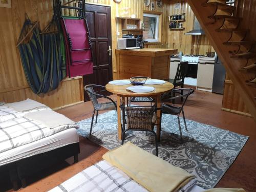 a room with a table and chairs and a kitchen at domki nad jeziorem, las, do 10 osób jezioro Wilczyńskie Budzisławskie - domek letniskowy osobno ogrodzony, ogrzewany mile widziane pieski, zwierzeta- wielkopolska, 62-550 Zygmuntowo gm Wilczyn in Zygmuntowo