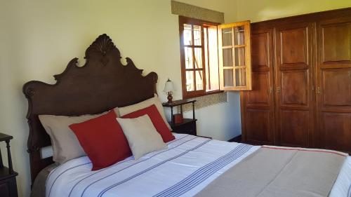 Schlafzimmer mit einem Bett mit roten und weißen Kissen in der Unterkunft Quinta Da Prova in Arcos de Valdevez