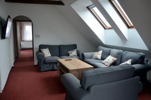 a living room with blue couches and a wooden table at Penzion U Cyrila in Moravská Třebová