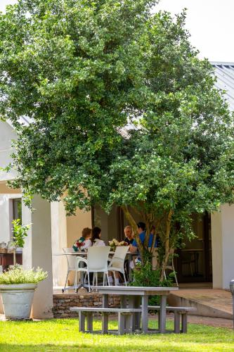 a group of people sitting at a table under a tree at Hamiltons Lodge & Restaurant in Malelane