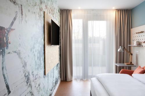 a bedroom with a bed and a tv on a wall at greet Wien City Nord in Vienna