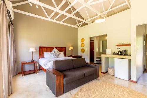 a bedroom with a bed and a couch at Hamiltons Lodge & Restaurant in Malelane