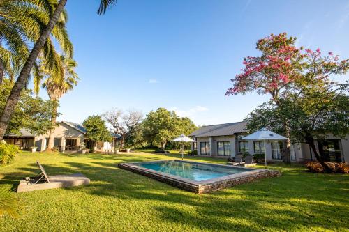 a backyard with a swimming pool and a house at Hamiltons Lodge & Restaurant in Malelane