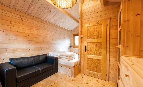 a room with a leather couch in a wooden cabin at Ośrodek Polaris in Dziwnówek