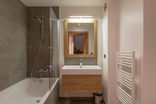 a bathroom with a sink and a tub and a mirror at Chalet Makalu in Les Gets