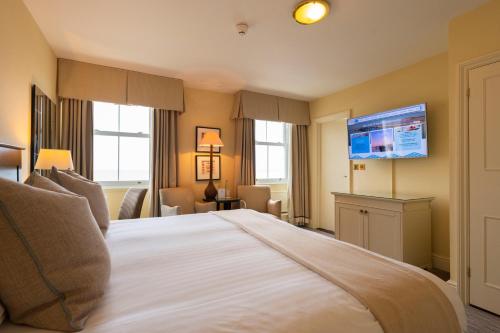 a hotel room with a large bed and a flat screen tv at St George's Hotel - Llandudno in Llandudno