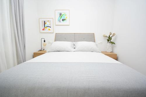 a bedroom with a large bed with white sheets at Apartamento frente al mar en Cambados in Cambados