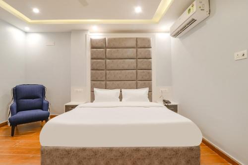 um quarto com uma cama grande e uma cadeira azul em FabHotel Av Royale em Dehradun