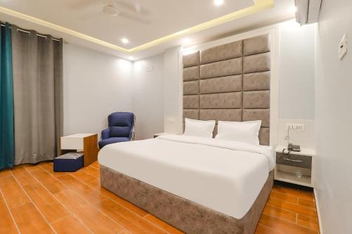 a bedroom with a large bed and a blue chair at FabHotel Av Royale in Dehradun