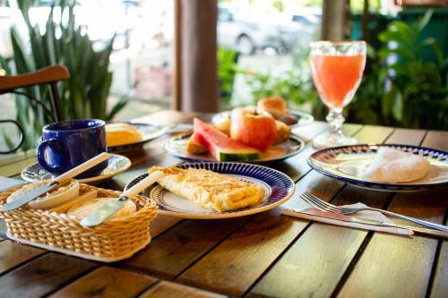 a wooden table with plates of food and a glass of orange juice at Pousada Pangea Tropical in Arraial d'Ajuda