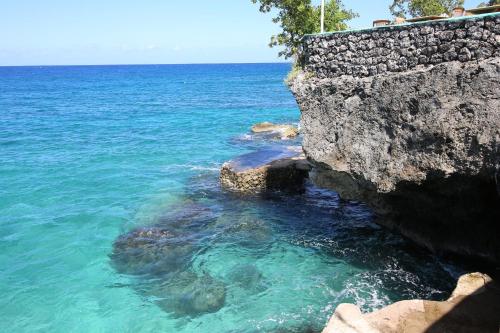 a rock wall next to the ocean with blue water at Xtabi Resort in Negril