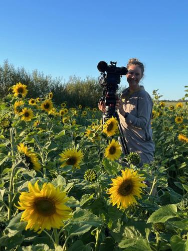 a man holding a camera in a field of sunflowers at Room 6 - Hawkraft Kulturhotel in Vestervig