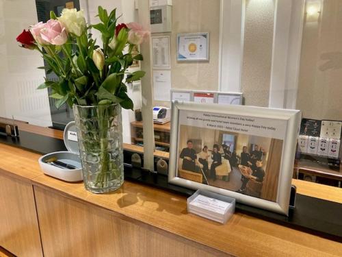 wazon kwiatów siedzący na ladzie ze zdjęciem w obiekcie Astor Court Hotel w Londynie