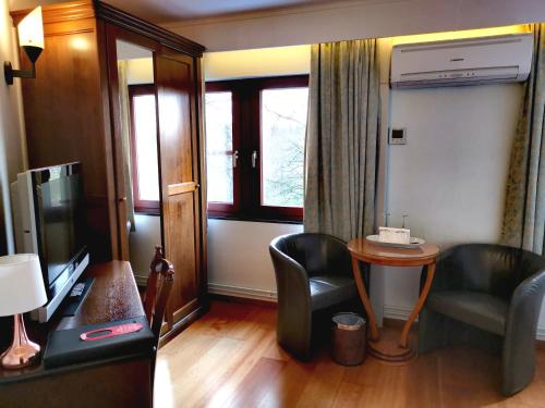 a hotel room with a tv and a table and chairs at La Roseraie. Gaume-Ardenne-lacuisine sur Semois. in Florenville