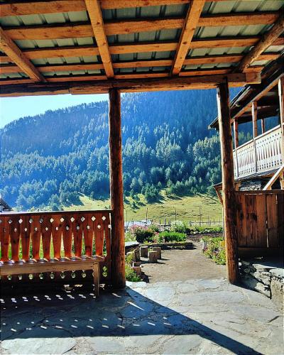 a wooden bench sitting on a porch with a view of a mountain at "Dzveli galavani" Tusheti Diklo "ძველი გალავანი" in Diklo