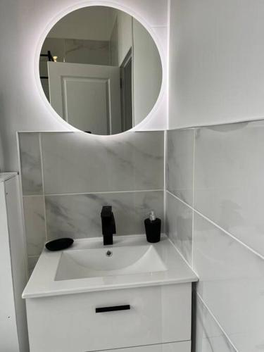 a bathroom with a white sink and a mirror at La Parenthèse Andelysienne in Les Andelys