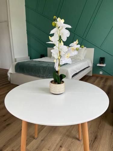 una mesa blanca con un jarrón de flores encima de una cama en La Parenthèse Andelysienne, en Les Andelys