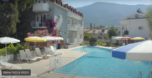 a swimming pool with chairs and umbrellas next to a building at New Golden Gate Butik Otel in Muğla