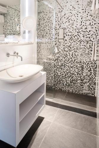 a white bathroom with a sink and a shower at Van der Valk Hotel Saint-Aygulf in Saint-Aygulf