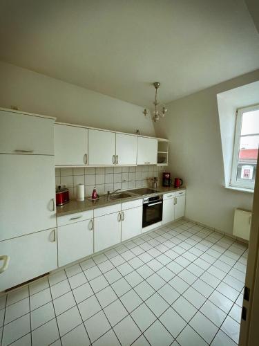 eine Küche mit weißen Schränken und Fliesenboden in der Unterkunft Talgarten Studio 6 in Erfurt
