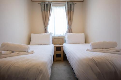 two beds in a small room with a window at Mersea Island by Away Resorts in Colchester