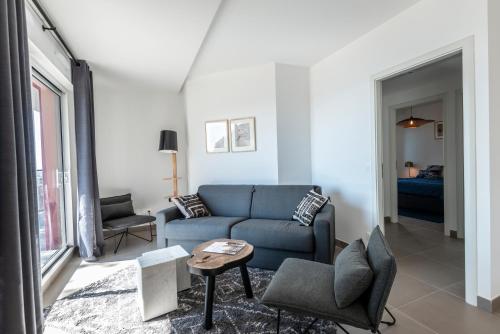 ein Wohnzimmer mit einem blauen Sofa und Stühlen in der Unterkunft Olydea Beausoleil in Beausoleil
