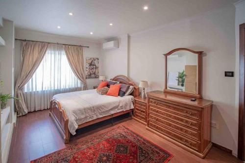 ein Schlafzimmer mit einem Bett, einem Spiegel und einer Kommode in der Unterkunft Pembroke St Julians Luxury, Comfort, Location in Pembroke