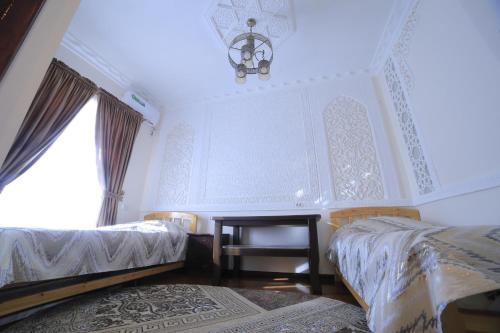 a bedroom with two beds and a chandelier at Hotel Hanifa in Bukhara