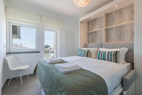 a bedroom with a large bed with a chair and a window at Green Oasis in Parede by LovelyStay in Parede