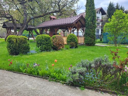 a garden with a gazebo and flowers at Casa ERNST in Moieciu de Jos