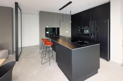 a kitchen with black cabinets and orange bar stools at Luxury Villa Cloer, Jadranovo - Sauna,Steam room, 2 Jacuzzis in Jadranovo