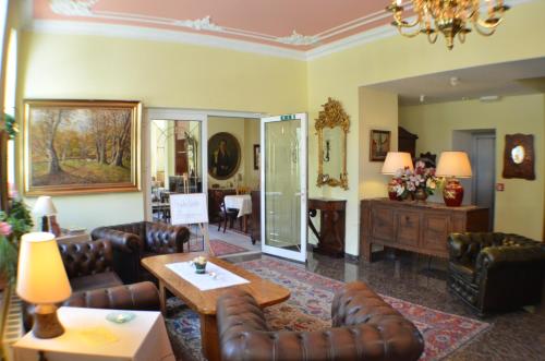 a living room with leather couches and a table at Hotel Fürstenhof in Rathenow