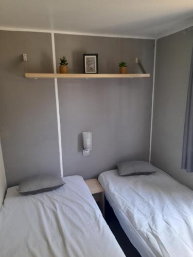 two beds in a small room with shelves at la dune blanche in Camiers