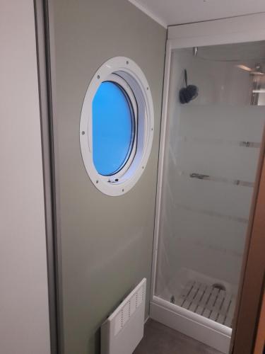 a bathroom with a round window and a shower at la dune blanche in Camiers