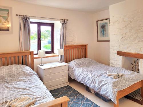 a bedroom with two beds and a window at Honeysuckle Bay Cottage in Brixham