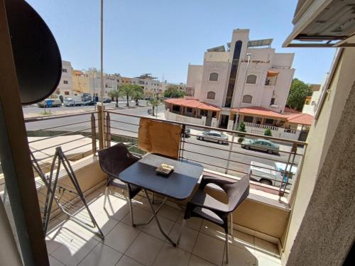 a table and chairs on a balcony with a view of a street at Sweet aqaba apartment in Aqaba