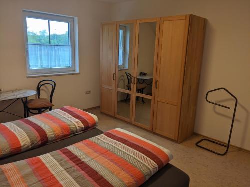 Cette chambre comprend 2 lits, une armoire et une table. dans l'établissement Ferienwohnung Lang, à Nittenau