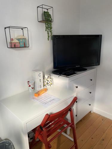 a white desk with a television and a red chair at Flanders Fields in Dingwall