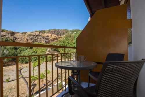 uma varanda com uma mesa e cadeiras e uma vista em En Plo Beachfront Rooms em Falasarna