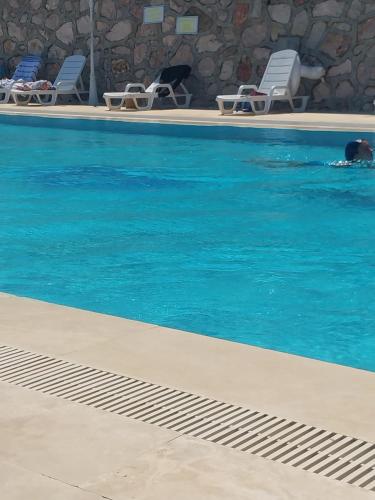 einen Pool mit Stühlen und blauem Wasser in der Unterkunft Arko sitesi in Karaburun