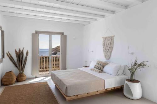ein weißes Schlafzimmer mit Bett und Balkon in der Unterkunft Villa Stephanie with heated pool, by Red Windmill Villas in Mykonos Stadt