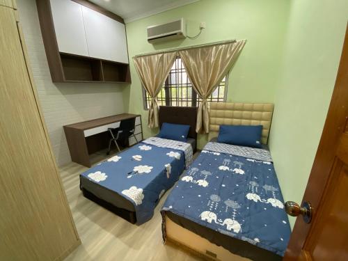 a bedroom with two beds and a desk and a window at Happiness Homestay in Mersing