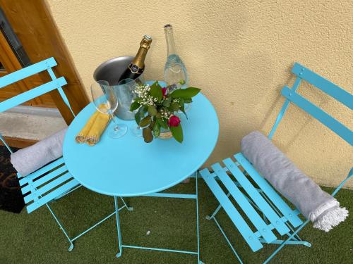 een tafel met 2 stoelen en een fles wijn en bloemen bij Le Nid Bourguignon in Chalon-sur-Saône