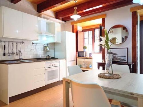 a kitchen with white cabinets and a table with chairs at Estudio El Ingenio de San Andrés in San Andrés