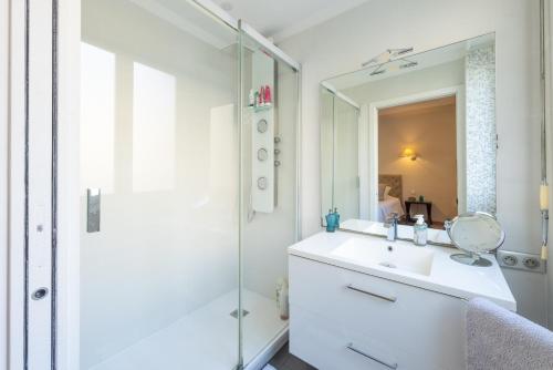 a white bathroom with a sink and a shower at Elégant appartement proche bord de mer in Beaulieu-sur-Mer