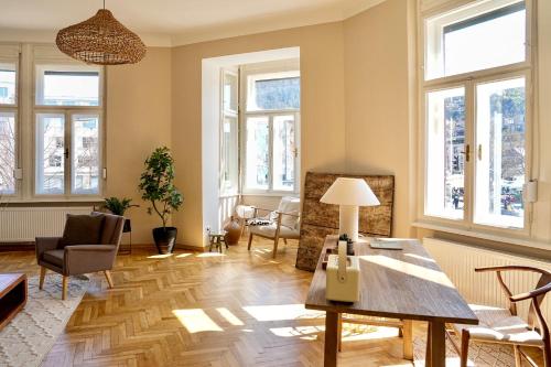 een woonkamer met een tafel, stoelen en ramen bij Altbau-Traum im Stadtzentrum in Graz